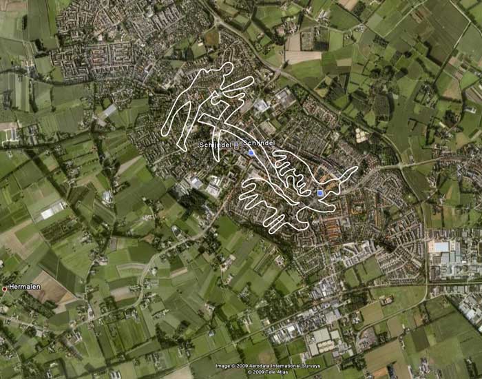 Een luchtfoto van de bebouwde kom van Schijndel. Hierop is een boer achter een eergetouw getrokken door twee ossen getekend. De tekening is gemaakt naar voorbeeld van grottekeningen uit het Noorden van Europa.