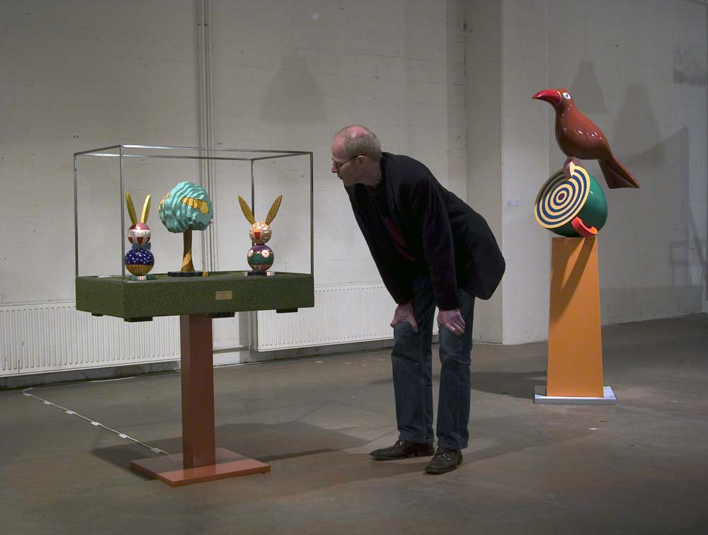 in een kader waar muziek uit komt, het walsje An der schönen blauen Donau, staan twee hazen, manlijk en vrouwelijk met in het midden een gekleurde boom. Het beeld wordt door een bezoeker tijdens de tentoonstelling bekeken, © André Boone