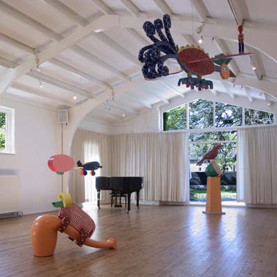 het interieur van de galerie met oa hangend aan het plafond een gekleurde caravan voortgetrokken door een vliegtuig, ©andré boone 